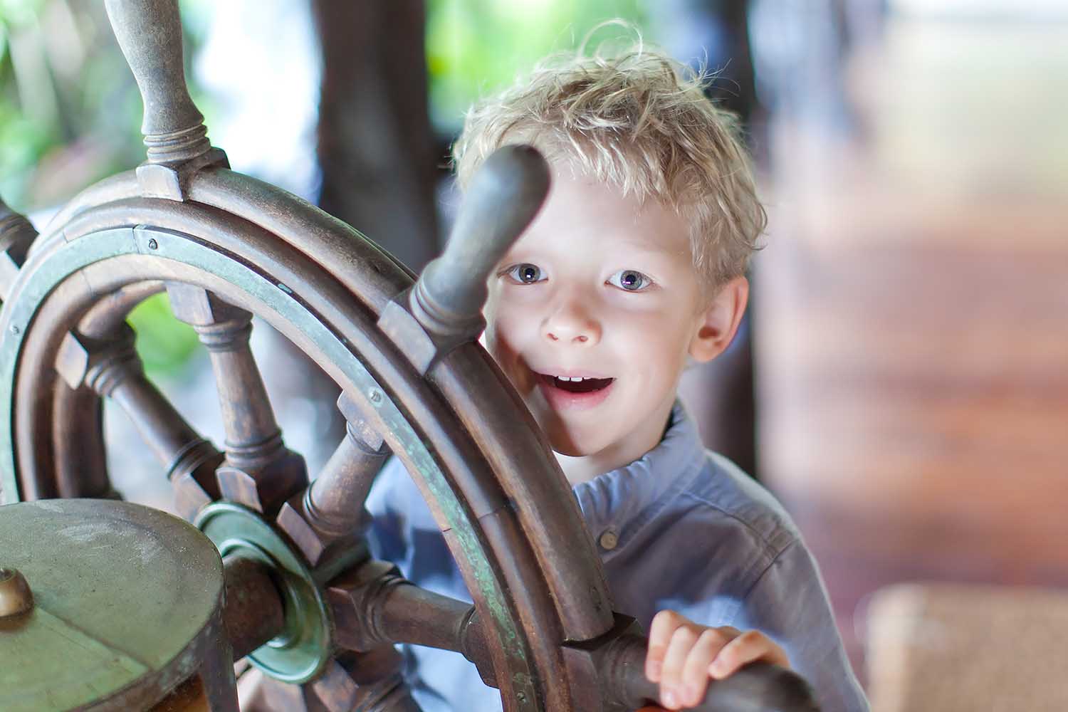 Happy boy guides a ship's steering wheel. 