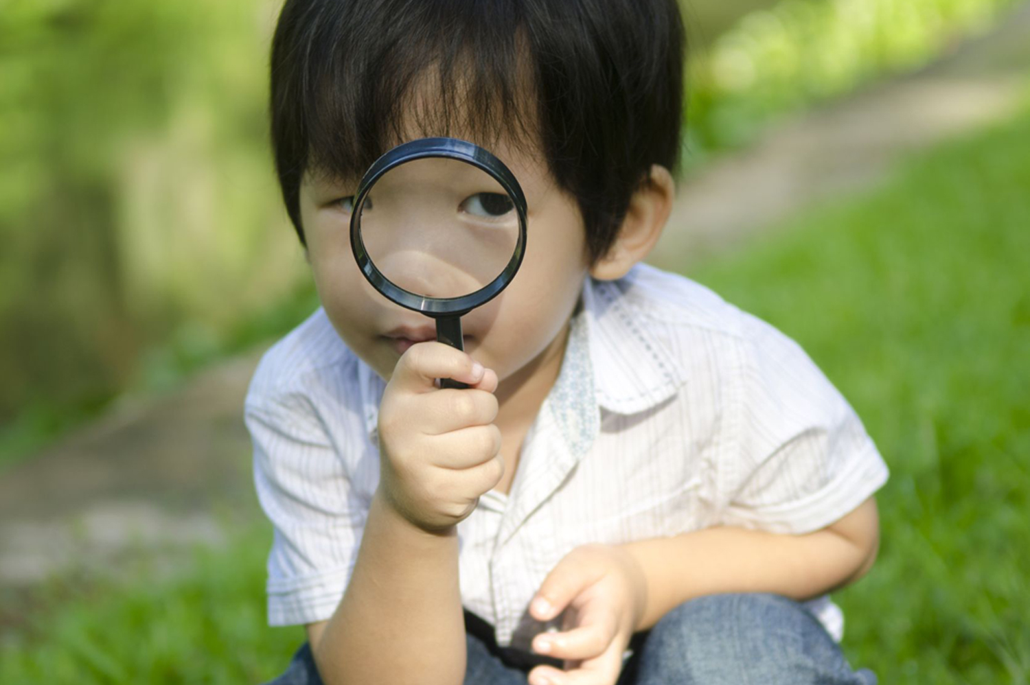 Little boy exploring nature by magnifier. 
