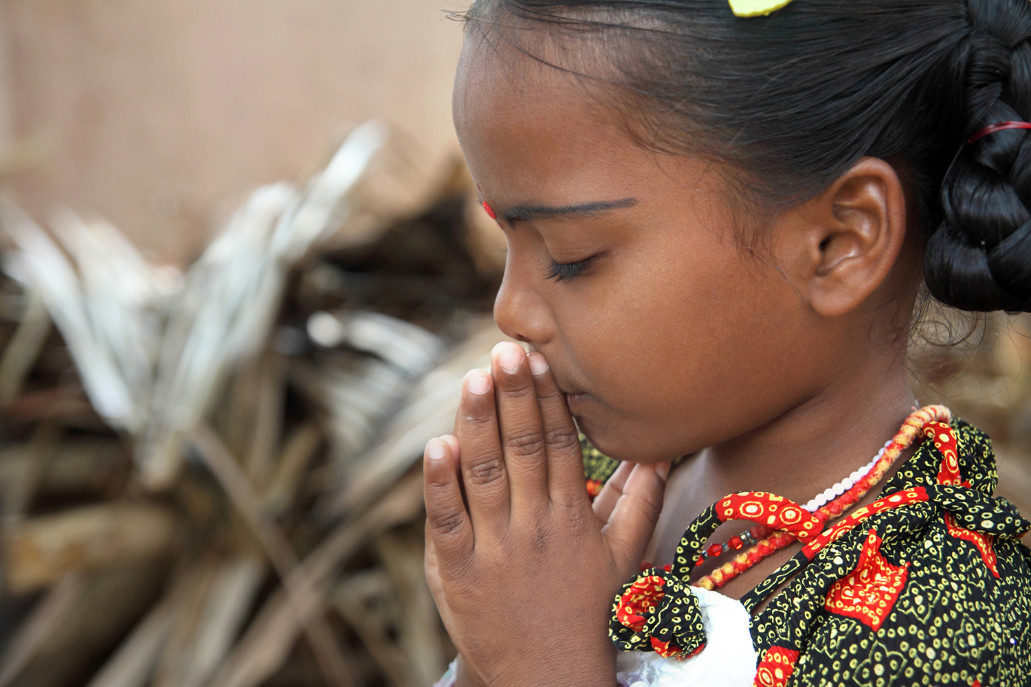 East Indian girl holds her hands together in prayer.