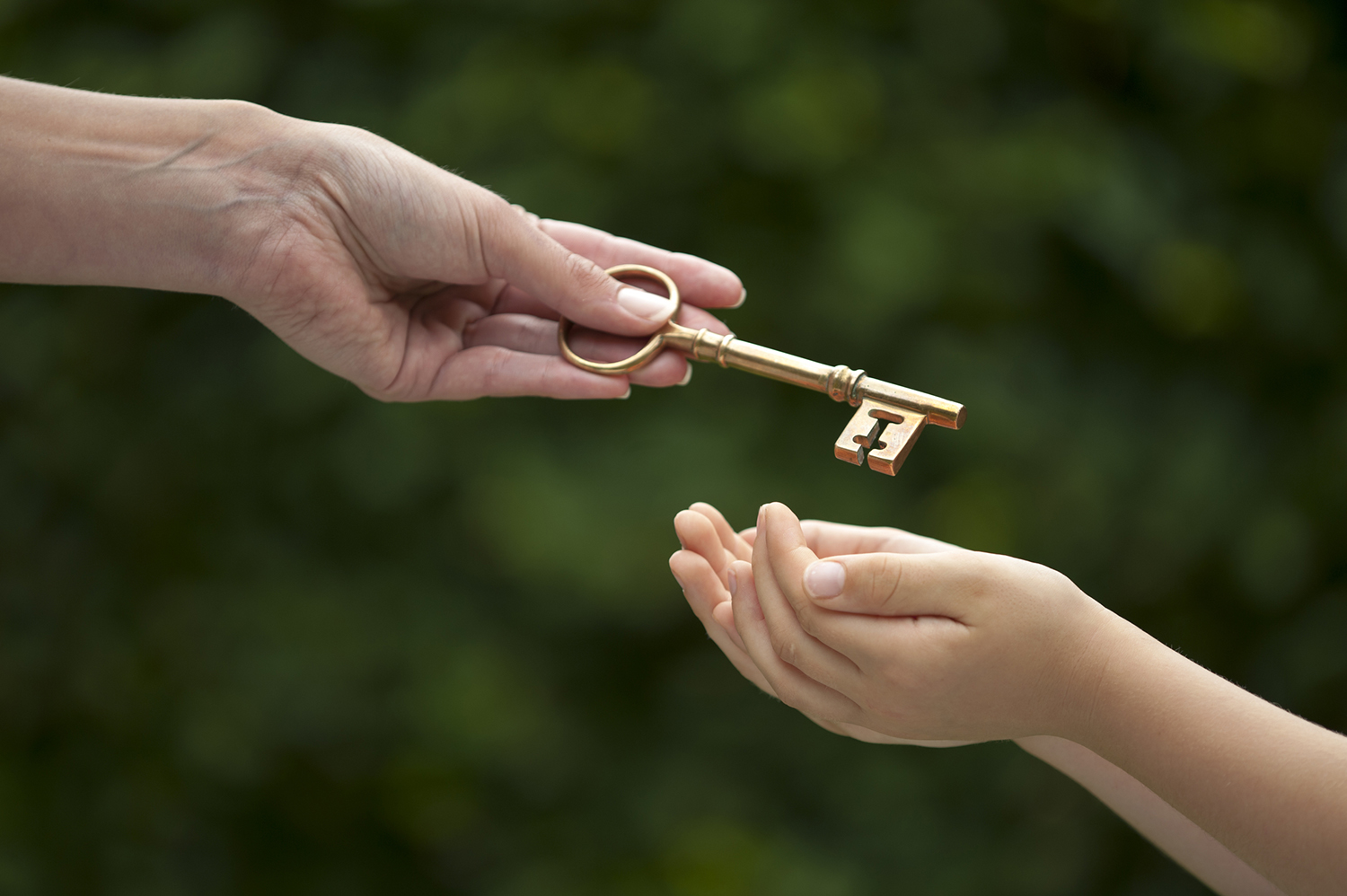 Mother hands shiny brass key to her young daughter.