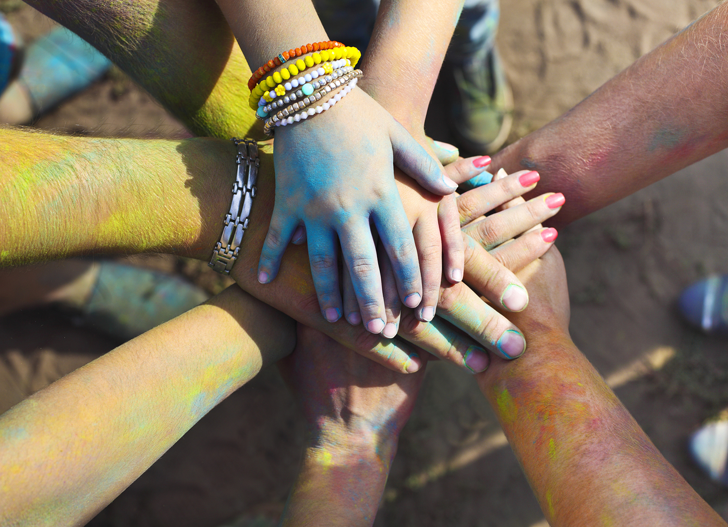 Friends at a Holi colors festival (India) join hands as a show of unity and teamwork.