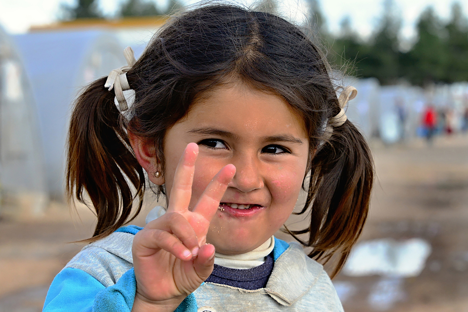 Syrian girl in refugee camp (Suruc, Turkey) holds peace hand sign. 