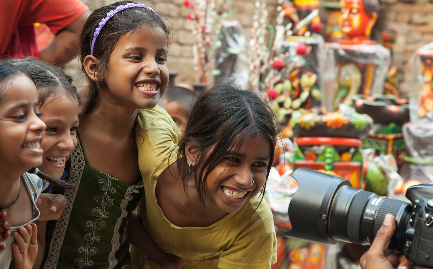 Happy East Indian girls pose for photographer on city street.