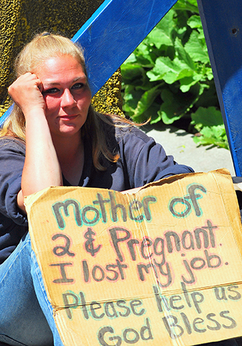 Homeless pregnant mother of two sitting on sidewalk holding sign "Please help".© Oscar C. Williams | Dreamstime.com