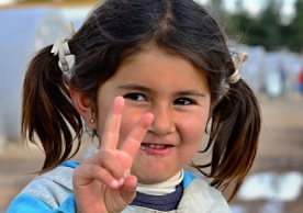 Syrian girl holding up peace sign in a Turkish refugee camp. (© Radek Procyk - Dreamstime.com)