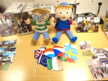 Two happy puppets sit upon on a desk with photographs - The Media Initiative for Children (N. Ireland).