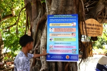 Young boy reads guidance tree sign on protection against the Covid 19 virus (Vietnam). © Poonsak Pornnatwuttikul, Dreamstime Images.
