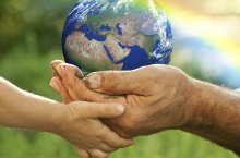 Young child and father caringly hold a blue-green Earth ball.